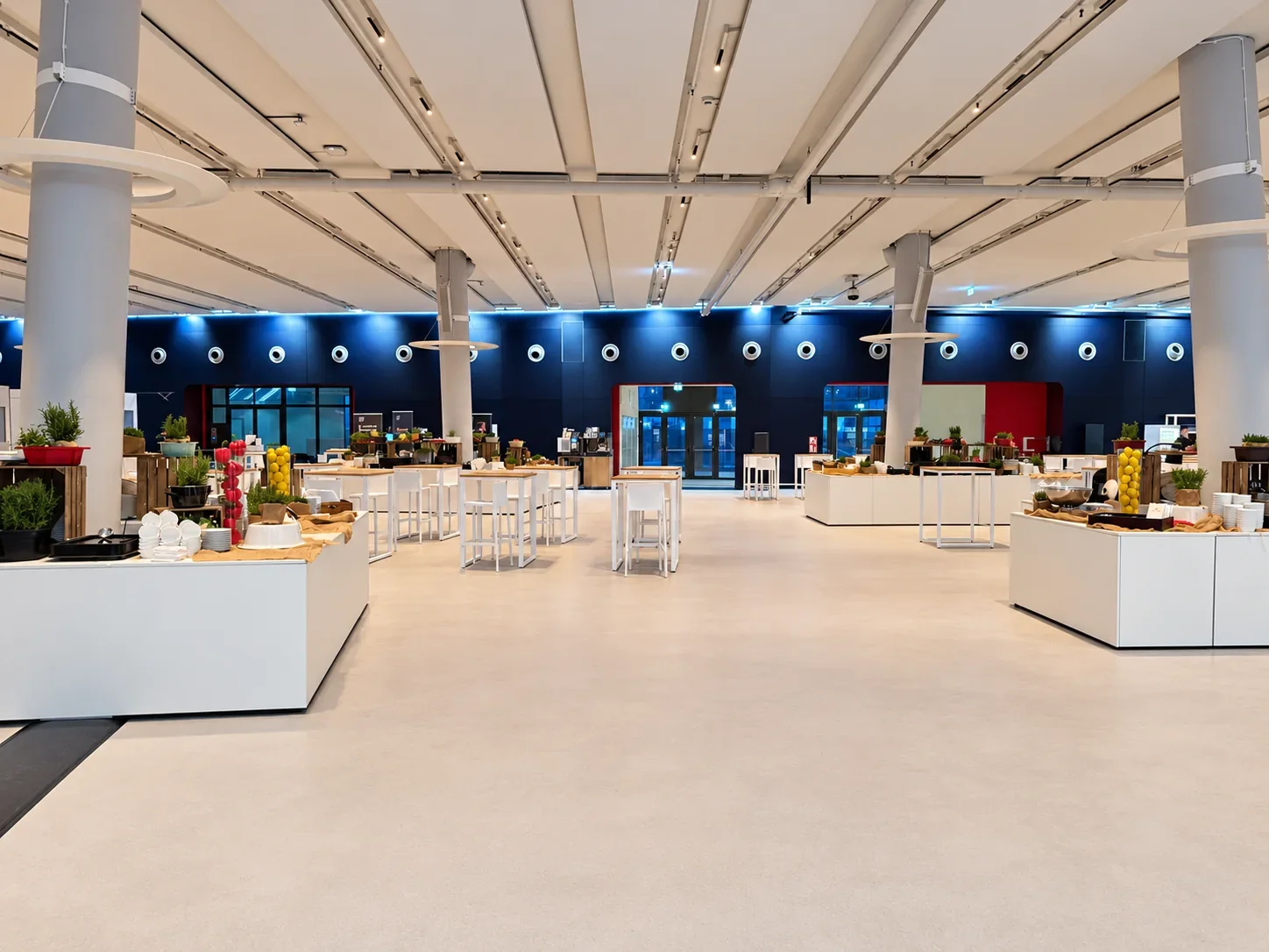 Breiter Gang zwischen weißen Buffetinseln und Hochtischen im Cruise Center HafenCity
