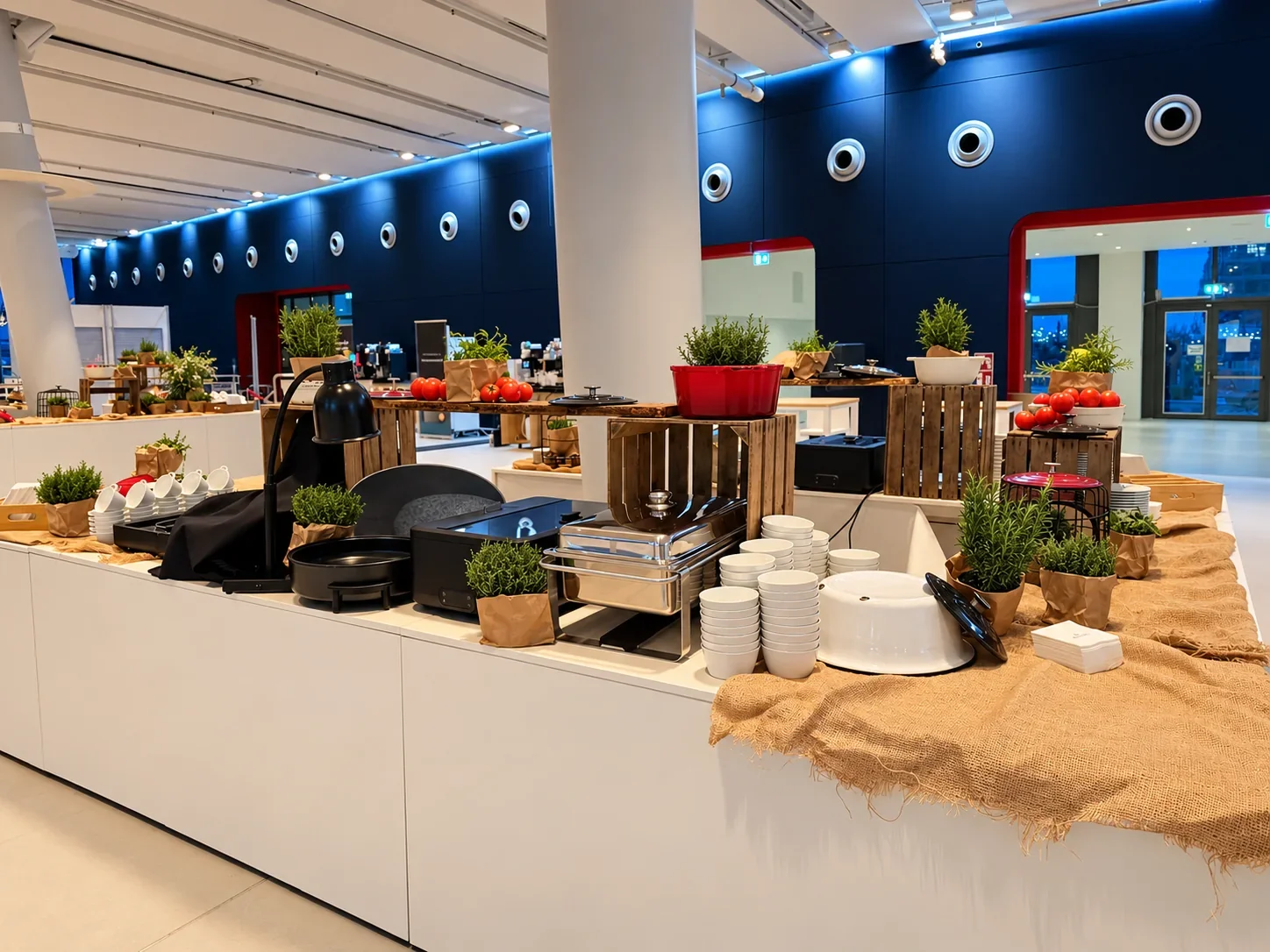 Seitliche Ansicht einer weißen Buffetstation mit Holzaufbauten und gestapelten Schalen im Cruise Center HafenCity