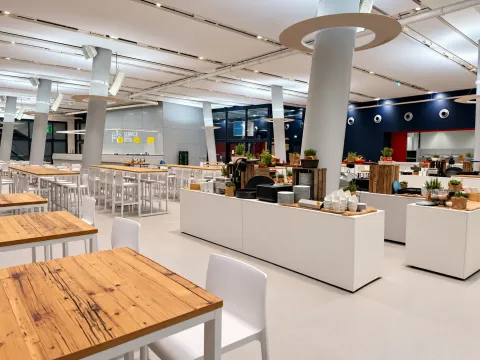Veranstaltungsraum im Cruise Center HafenCity mit weißen Hochtischen, Barhockern und aufgebauten Buffetinseln