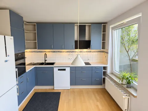 Schieferblaue Kundenküche mit heller Arbeitsplatte, offenen Regalen und seitlichem Fenster